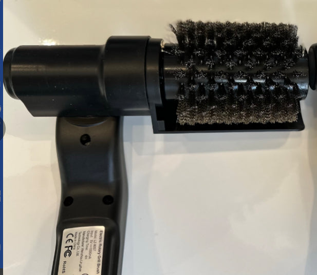 Electric BBQ grille brush by Velorian Collection cleaning heavy grease and grime from grill grates with rotating wire bristles.